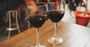 Two wine glasses with red wine in them, sitting on a wooden table
