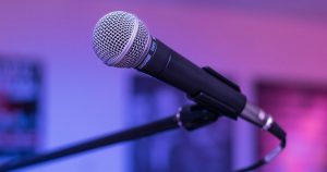 a microphone on a stand with blue and purple lighting in the background
